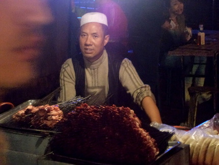 Man selling lamb skewers in the night market, Lanzhou China